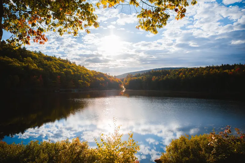 A still Maine lake ringed by autumn trees at sunrise